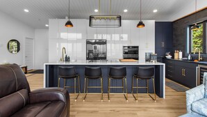 Una cocina moderna con una isla central, taburetes de bar e iluminación colgante.