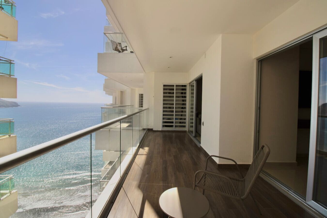 Un balcon avec vue sur l’océan, une porte vitrée et une chaise.