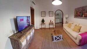 Een woonkamer met een televisie, een bank, een salontafel en een kleine kerstboom.