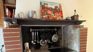 Een keuken met bakstenen muren, een inbouwoven, hangende pannen en een plank met een decoratief object.