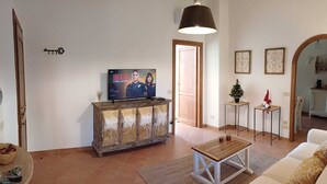 Een woonkamer met een televisie, een houten kast, een salontafel en een bank.
