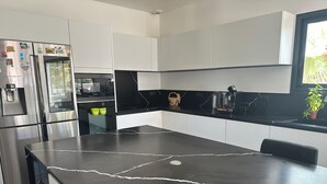 A modern kitchen with a black marble countertop, stainless steel appliances, and white cabinetry. - Villa with private pool in a quiet location 10 min from Avignon (ROCHEFORT DU GARD)