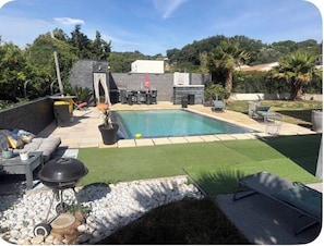 Un jardin avec une piscine, un espace salon extérieur et un coin barbecue.