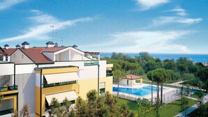 A modern residential building with a swimming pool, surrounded by greenery and a view of the sea. - Beautiful flat with large garden and terrace (Bibione)