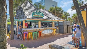 Un bar junto a la playa llamado Marco Polo con terraza y un tablero de menú.