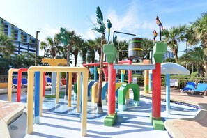A playground with colorful play structures, palm trees, and a lifeguard duty sign. - Cool Coast Ocean View Resort Studio (Myrtle Beach)