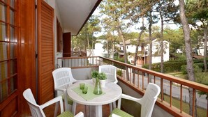 A balcony with a round table, four white chairs, and a potted plant.