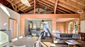 A spacious loft with a high ceiling, a dining area with a long table and chairs, a sofa, and a kitchen area with a window. - Stunning private villa for 8 people with WIFI, TV, terrace and panoramic view (Ovronnaz)