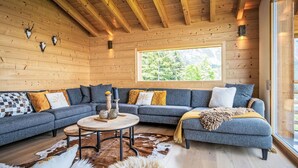 Ein gemütliches Blockhaus-Interieur mit einem großen Ecksofa, einem runden Couchtisch und einem Cowhide-Teppich.