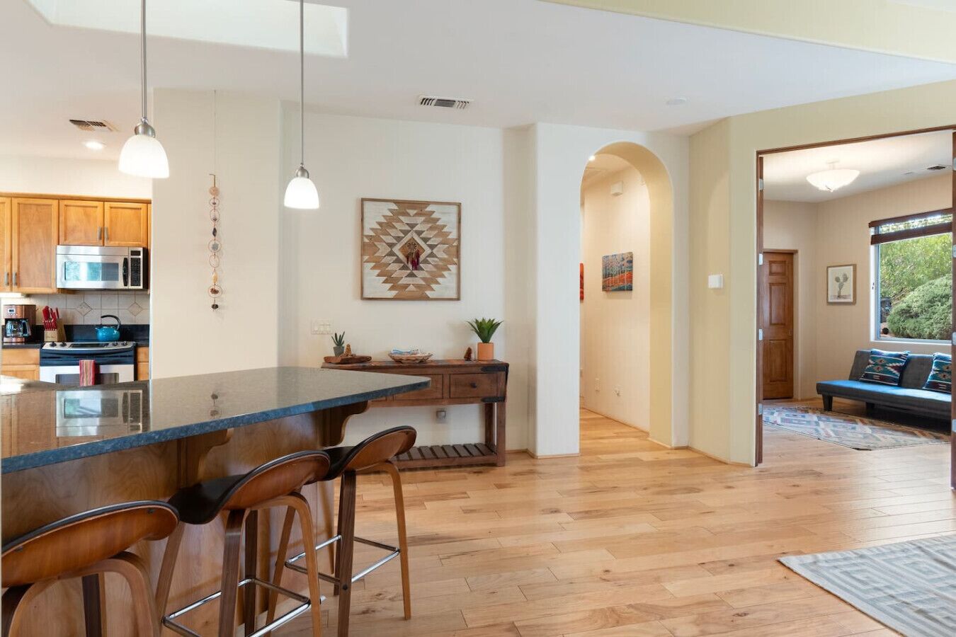 Une cuisine moderne dotée d’un grand îlot central, de tabourets de bar en bois et de luminaires suspendus.