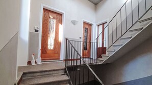 Una escalera conduce a un rellano con dos puertas de madera, cada una con un panel de vidrio decorativo.