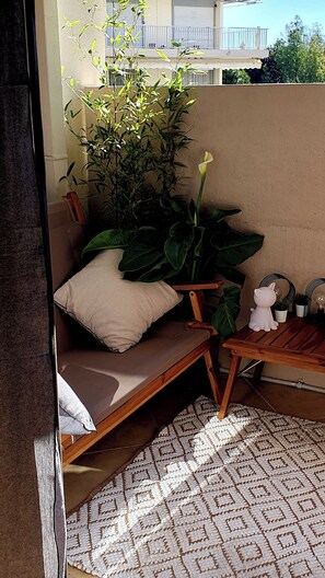 A small, cozy seating area with a cushioned bench, a white pillow, and a potted plant. - Apartment 2 pers Residence PISCINE Mandelieu La Napoule Beaches 15mn walk (Mandelieu-la-Napoule)