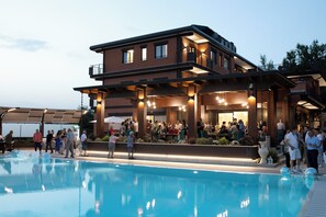 A modern hotel with a pool, outdoor seating, and a covered patio area. - Lual Bleisure Hotel  (Pofi)