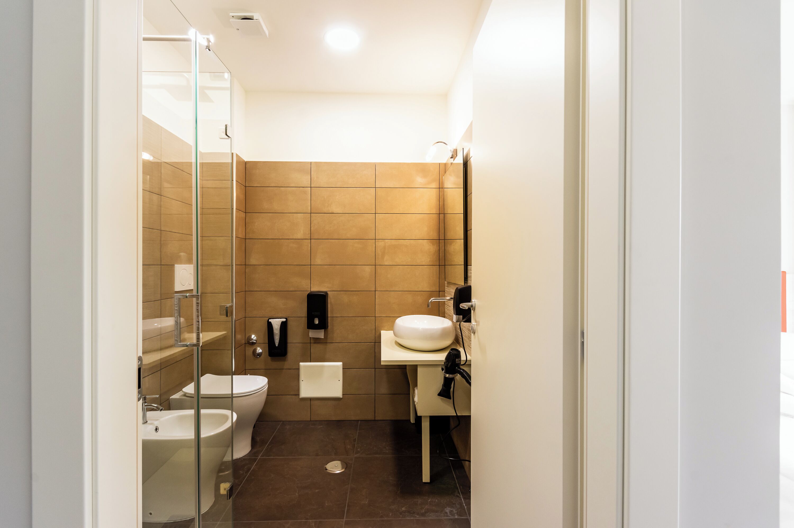 Une salle de bain moderne avec une douche à parois de verre, des toilettes, un bidet et un lavabo.