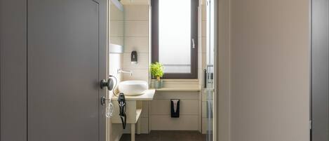 Un baño moderno con un espejo grande, un lavabo blanco, una ventana pequeña y un perchero para toallas.