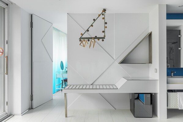 A modern, minimalist room with a geometric wall design, a built-in desk, and a visible kitchen area. - BoxDuoDuo (Wujie)