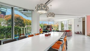 A spacious modern dining area with a long table, orange chairs, and two unique spherical pendant lights. - BoxDuoDuo (Wujie)