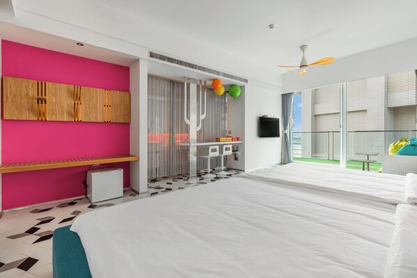 Quarto de hotel moderno com uma cama grande, um banco, uma pequena cozinha e varanda com vista.