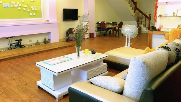 Una sala de estar moderna con un sofá, una mesa de centro y un televisor montado en la pared. Se ve una escalera que sube a otro nivel.