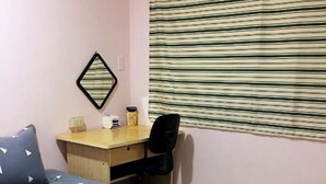 Una habitación de hotel con cama, escritorio, silla y ventana con persianas.