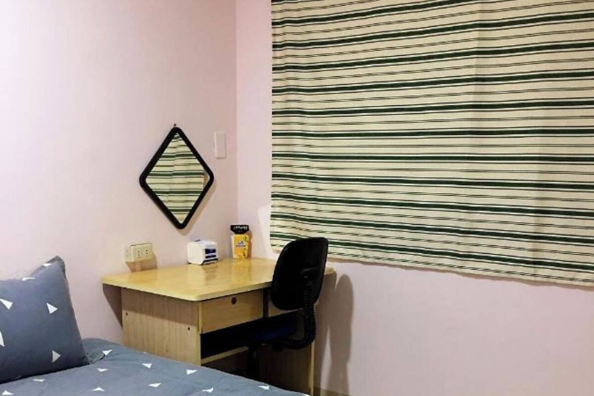 A hotel room with a bed, a desk, a chair, and a window with blinds.