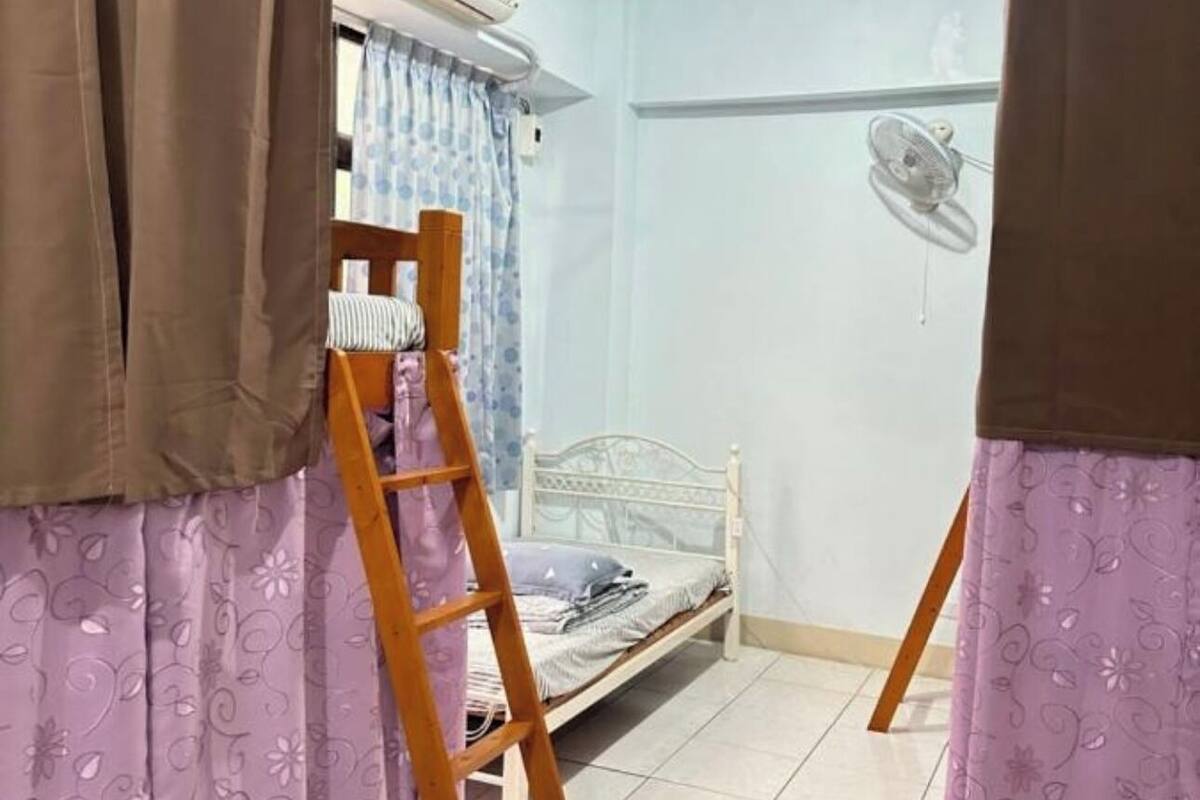 A room with a bed, a ladder, and curtains.