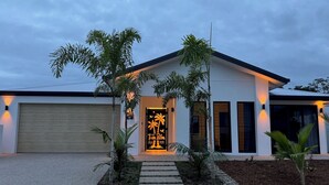 Uma casa moderna com garagem, entrada bem iluminada e jardim frontal ajardinado.