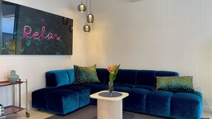 Uma sala de estar moderna com um sofá azul escuro, uma mesa de centro redonda e um ar condicionado fixado na parede.