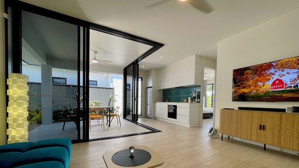 Uma sala de estar moderna com um sofá azul, uma mesa de centro e uma TV fixada na parede.