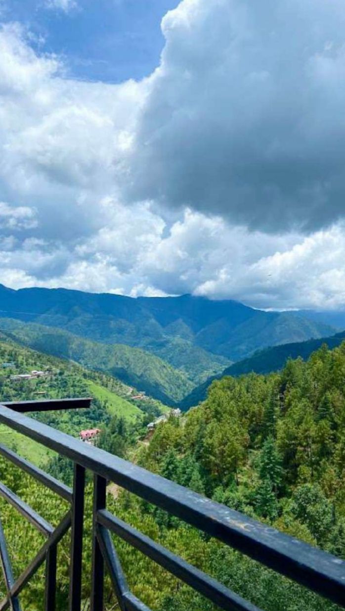 A mountainous landscape with a view of a valley and a distant building.