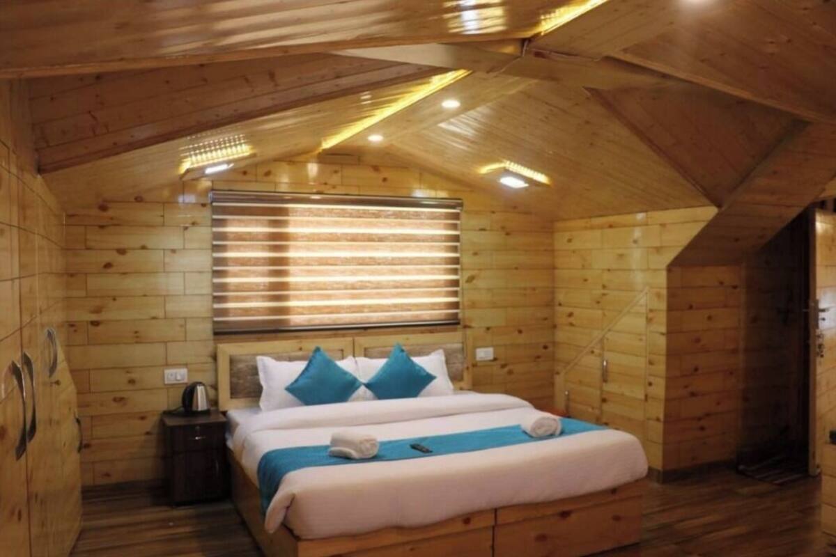 A wooden cabin room with a bed, a nightstand, and a window with blinds.