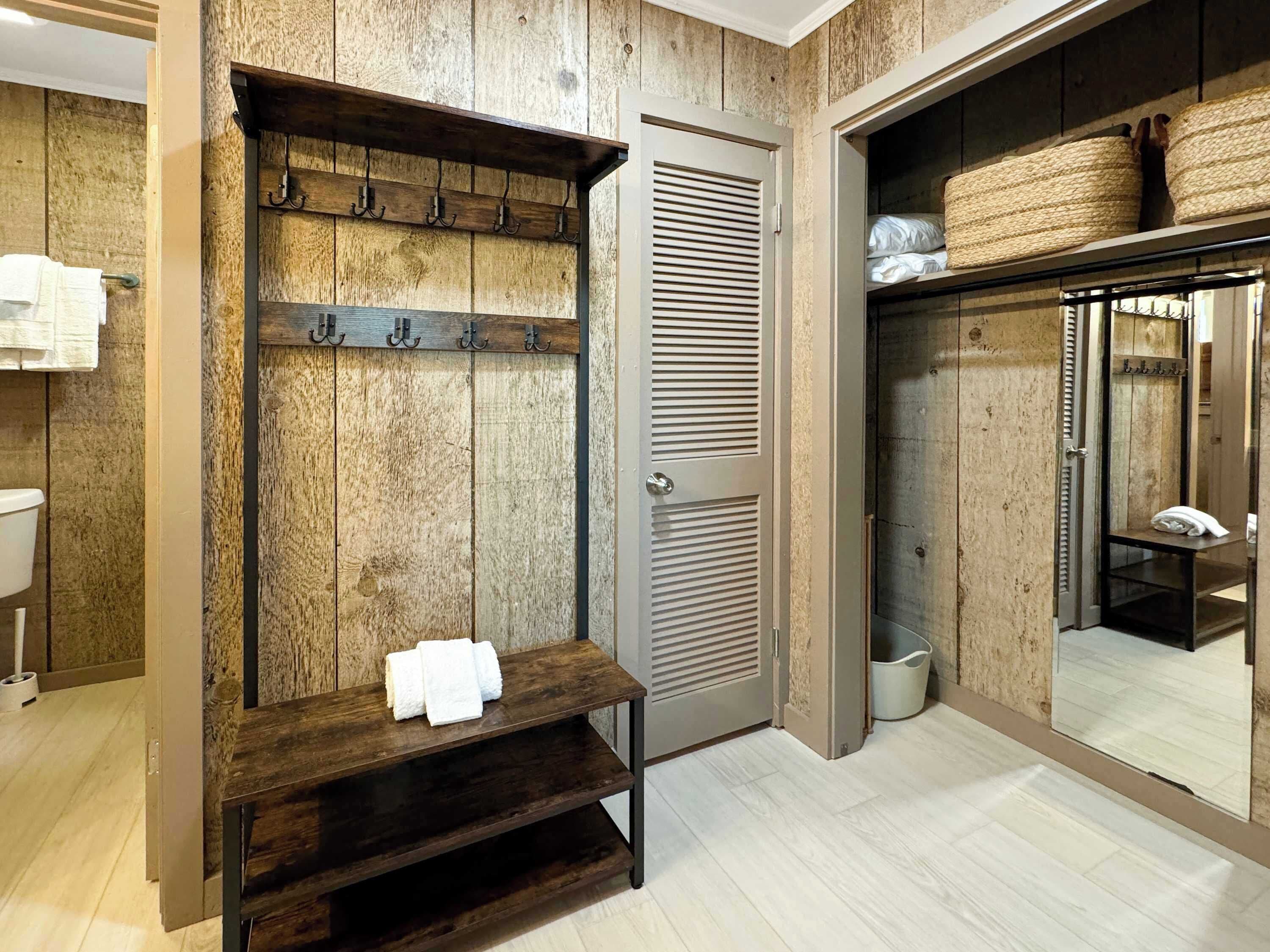 Een badkamer met een houten wand, een handdoekhouder, een bankje, een toilet en een spiegel.