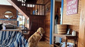 A cozy room with a dog, wooden walls, a blue door, and a sign that says "GO JUMP IN THE OCEAN". - Ocean views, private beach, garden patio, red clay tennis, dock access, WiFi (Boothbay Harbor)
