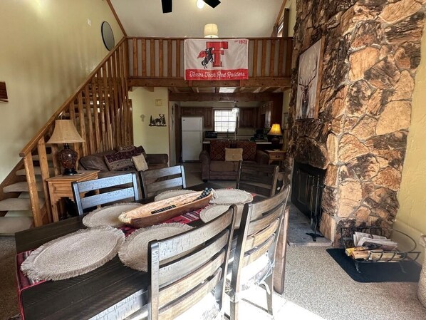 Amplia sala de estar con chimenea de piedra, muebles de madera y un banderín de Texas Tech Red Raiders.
