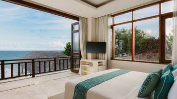 Habitación de hotel con una cama grande, un televisor en un mueble bajo y un balcón con vistas al mar.
