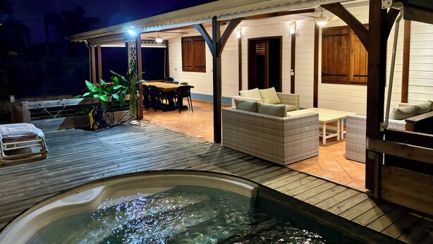 Et overdækket udeområde med jacuzzi, træterrasse og siddepladser.