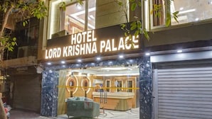The exterior of Hotel Lord Krishna Palace with a modern facade, a reception area visible through the glass, and a green lawn in front. - Hotel Lord Krishna Palace  (New Delhi)
