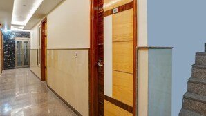 A hallway with a marble floor, wooden and beige wall panels, and a staircase on the right. - Hotel Lord Krishna Palace  (New Delhi)