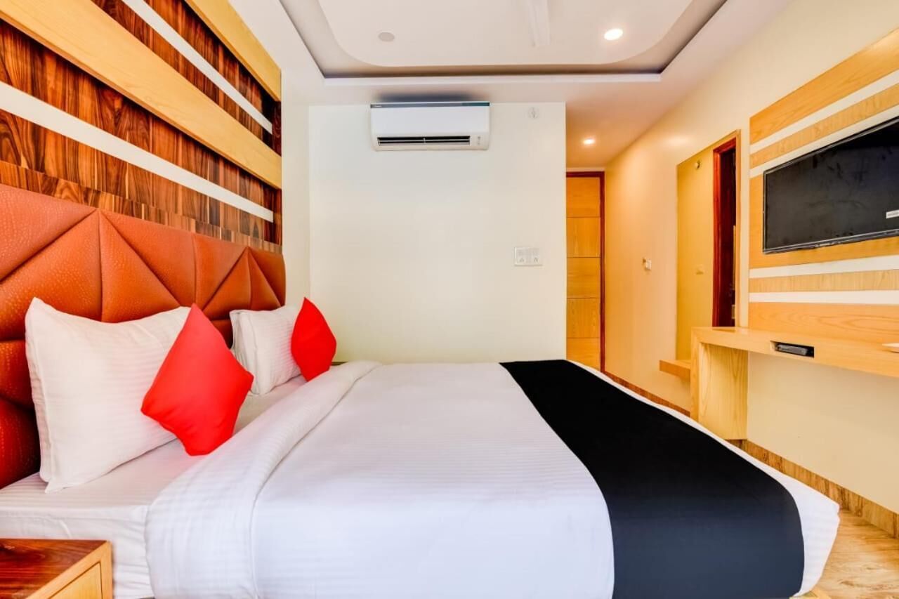 A hotel room with a bed, a TV, and a wooden headboard.