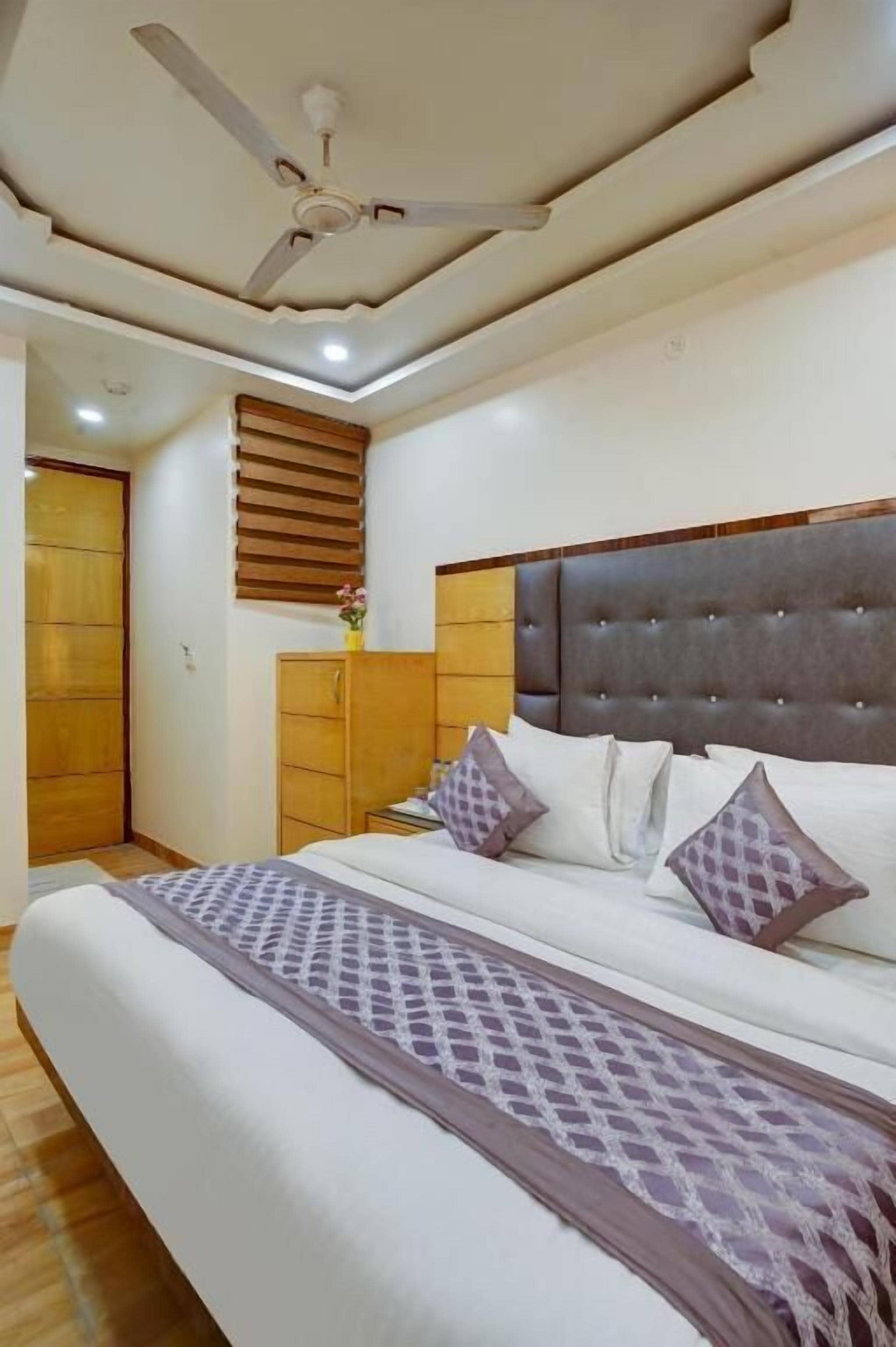 Un dormitorio con una cama, un ventilador de techo, un armario de madera y una ventana con persianas.