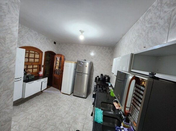 A compact kitchen with white cabinets, a stainless steel refrigerator, a stove, and a microwave.