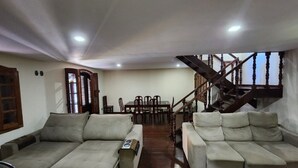 Ein geräumiger Wohnbereich mit zwei Sofas, einem Esstisch und einer Treppe.