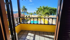Ein Balkon mit Blick auf einen Strand, Palmen und einen Pool.