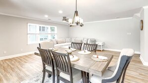 A spacious dining area with a wooden table, dark chairs, and a chandelier.
