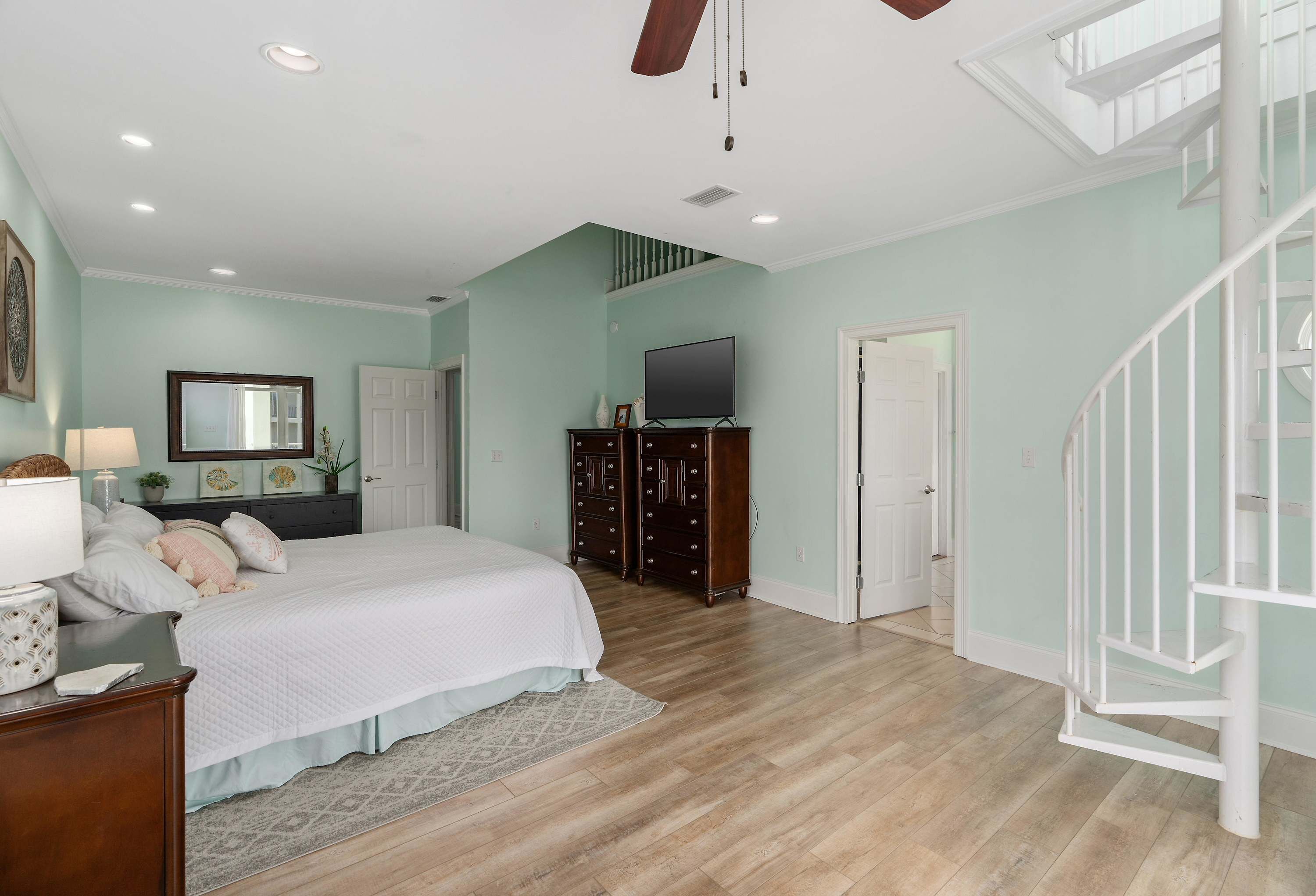 Une chambre à coucher avec un lit, une commode, un téléviseur et un escalier.