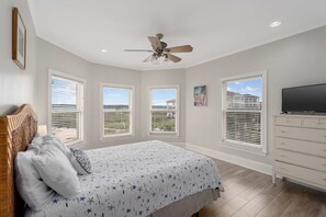 Un dormitorio con cama, ventilador de techo, cómoda y televisor.