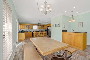 Una cocina amplia con armarios de madera, una isla central con taburetes y una gran mesa de comedor.