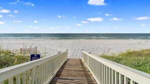 A wooden boardwalk leading to a beach with a 'Swim at Own' sign. - Laguna Sunset Elevator Beach Access (Gulf Shores)