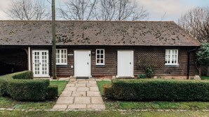 A wooden house with a front porch, two white doors, and a small garden with hedges. - Garden Lodge - pet friendly (Aston Tirrold)