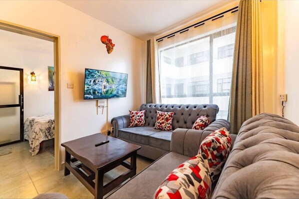 A living room with a grey sofa, a coffee table, and a TV mounted on the wall.